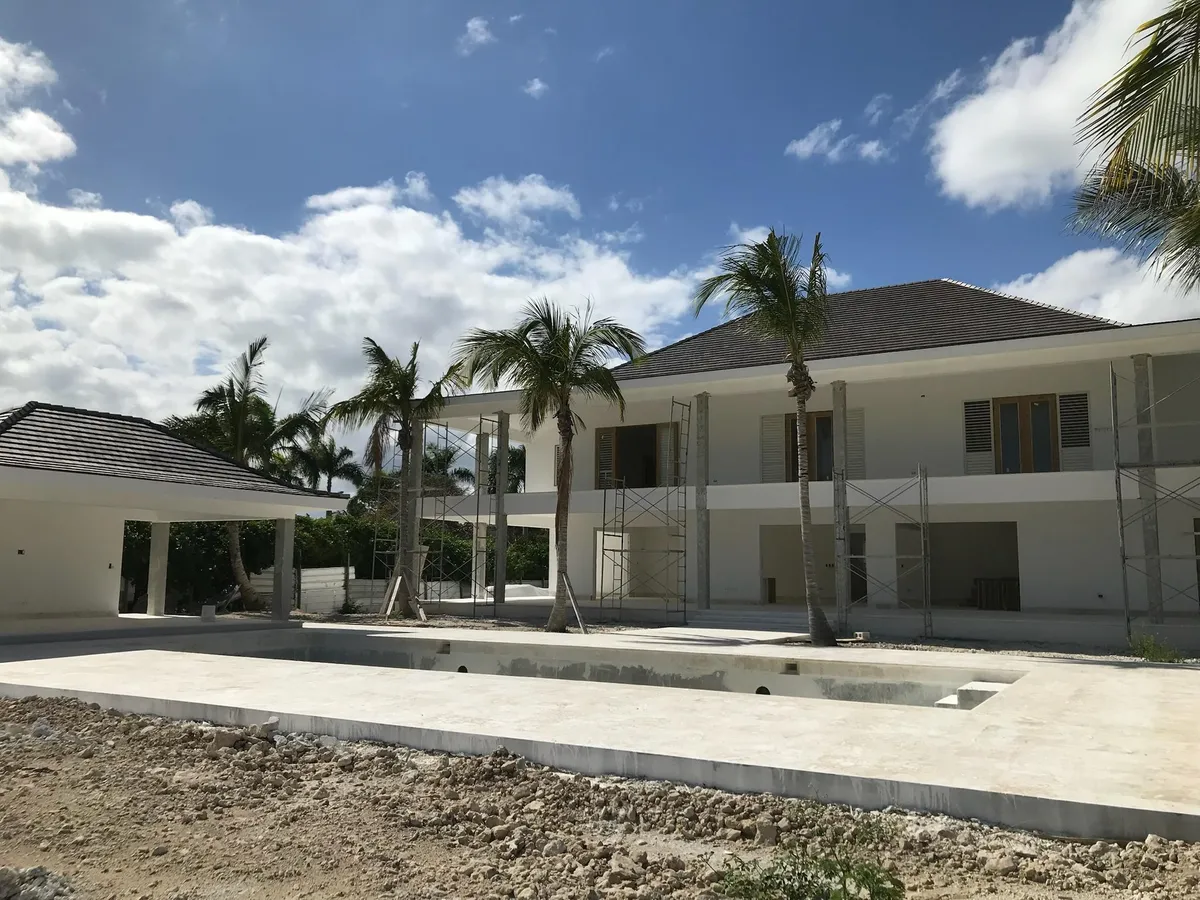 Two-story villa and unfinished pool during construction, with scaffolding along the facade