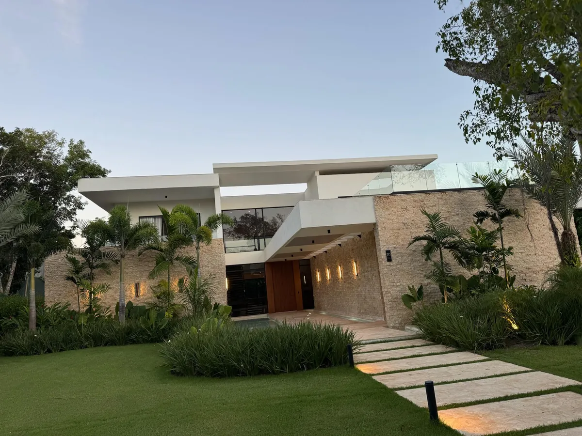 Stone-clad entrance of a contemporary villa at dusk, with wall sconces and a lit stepping-stone path